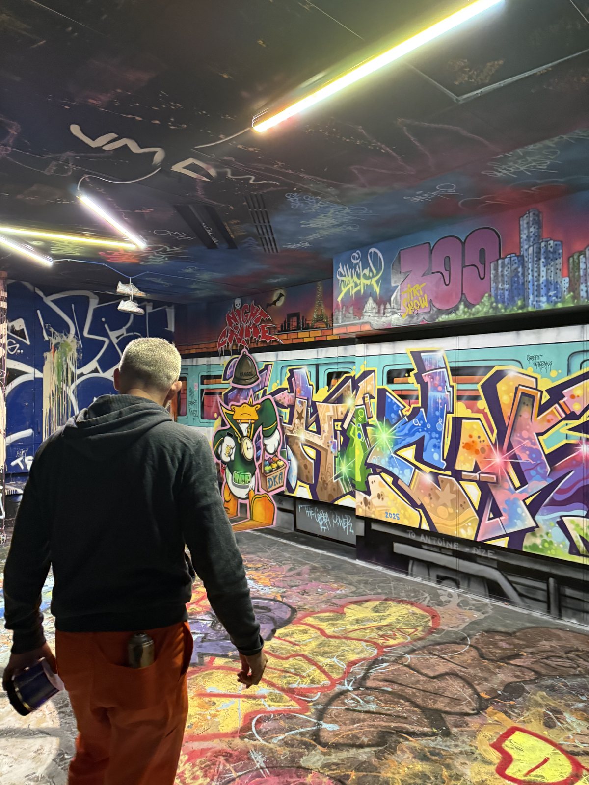 Un graffeur devant une fresque, dans un tunnel entièrement peint.